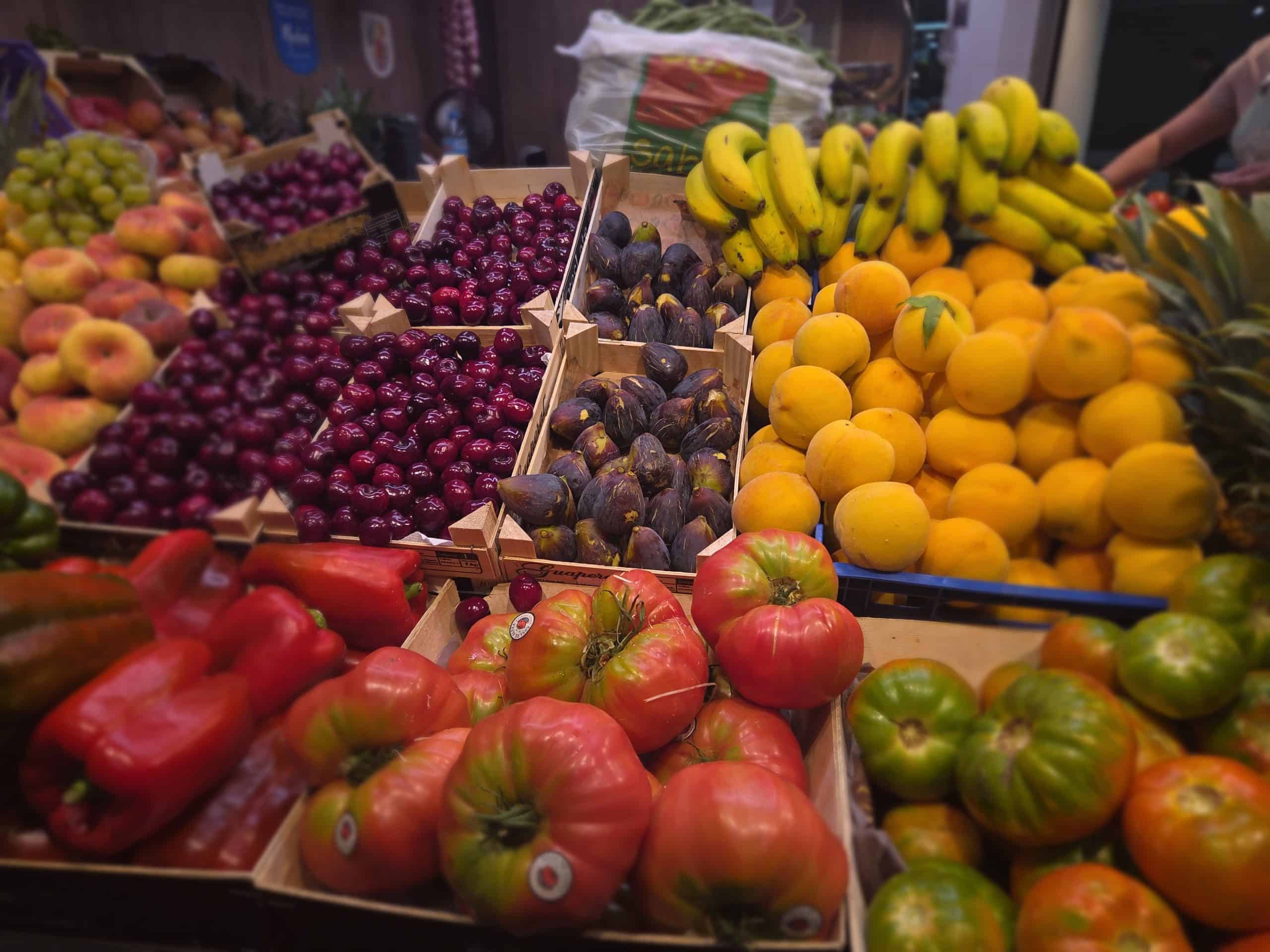 Frisse kleurrijke fruitscène met kisten vol kersen, vijgen, perziken, bananen en meloenen, vers en aantrekkelijk gepresenteerd op de markt bij Casa la Pluma.